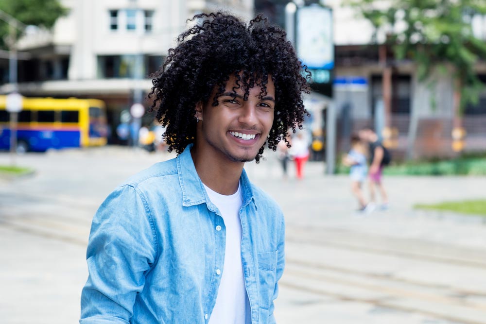 young man with long curly hair outdoor in city