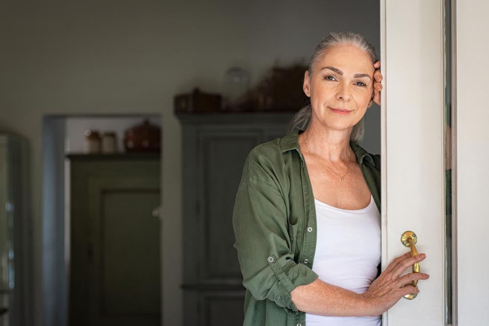 senior woman leaning against door at home